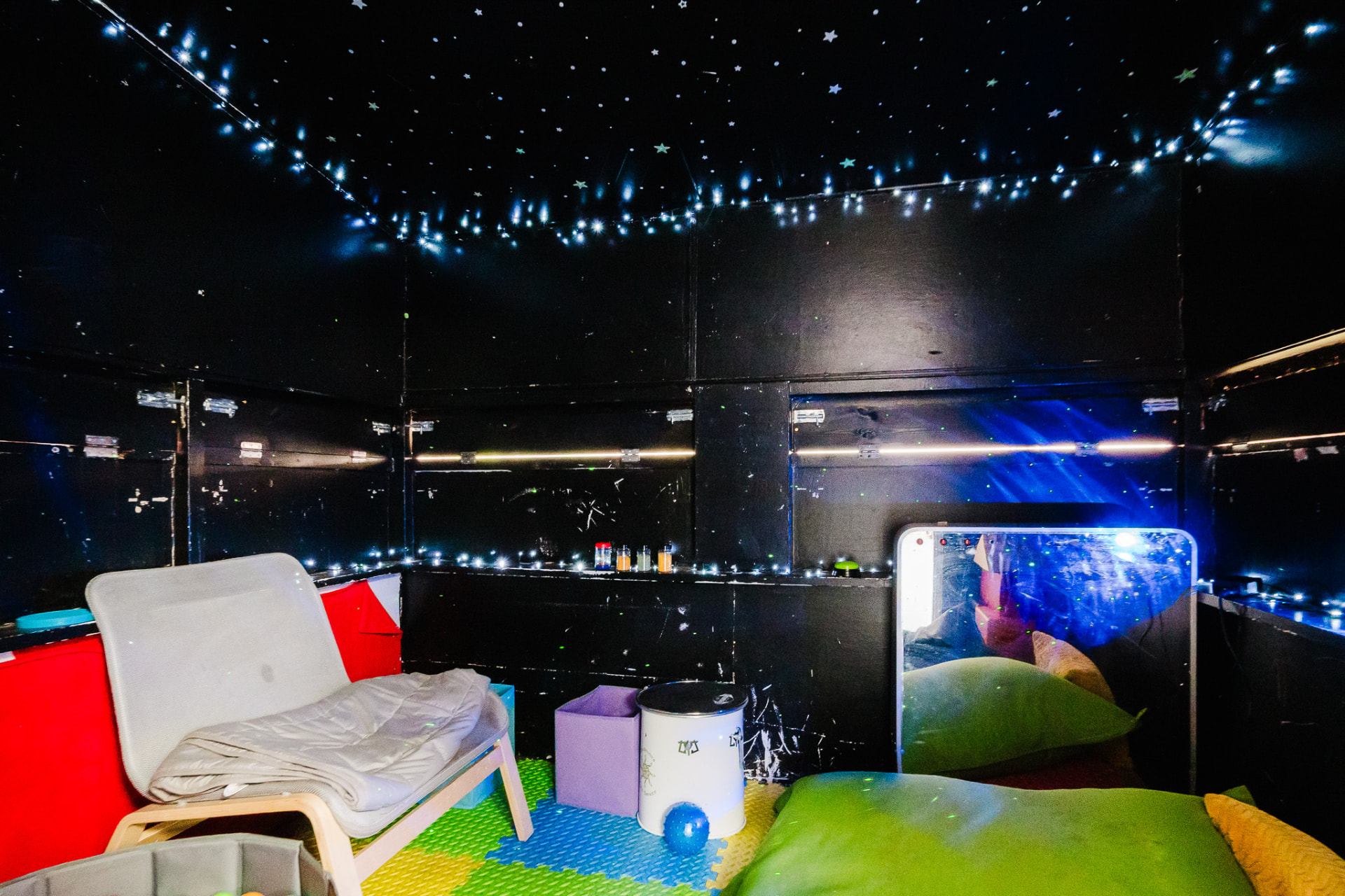 Dark sensory room with star lights and soft seating